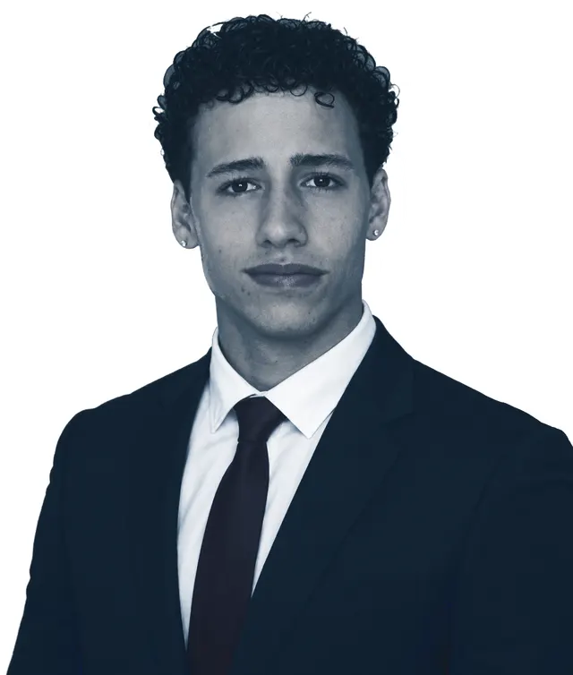 Enzo, in a dark suit and a white shirt, looking straight at the camera.